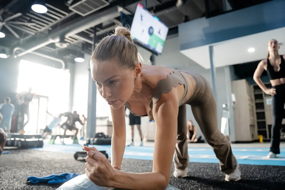 Woman holding a plank on the gym floor at SWEAT440
