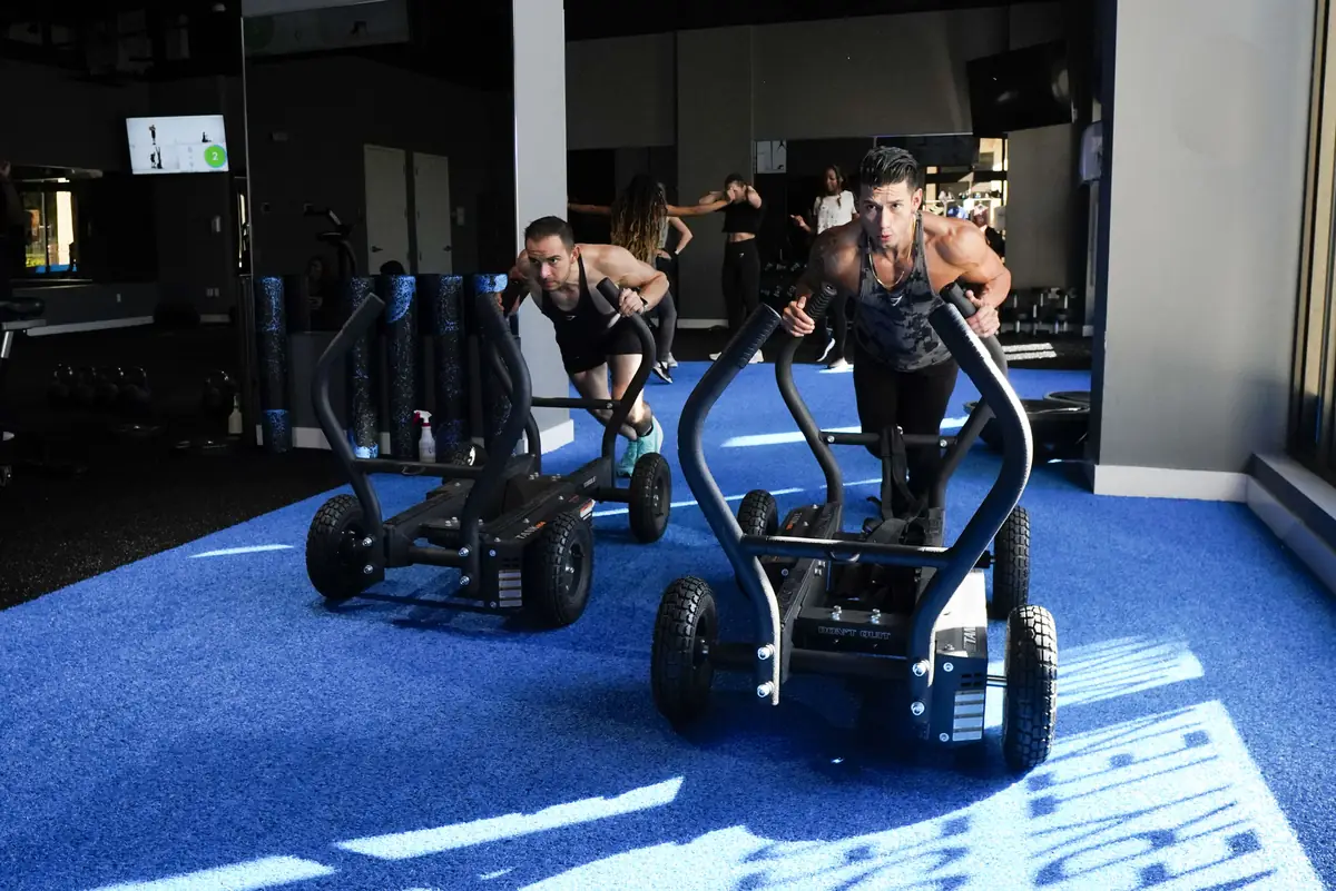 Members pushing weighted sleds across the turf at SWEAT440