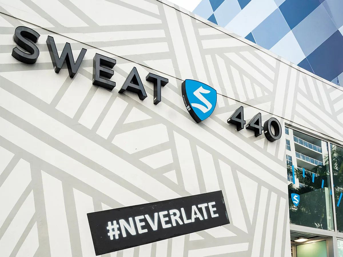 SWEAT440 studio exterior sign with the #NEVERLATE tagline