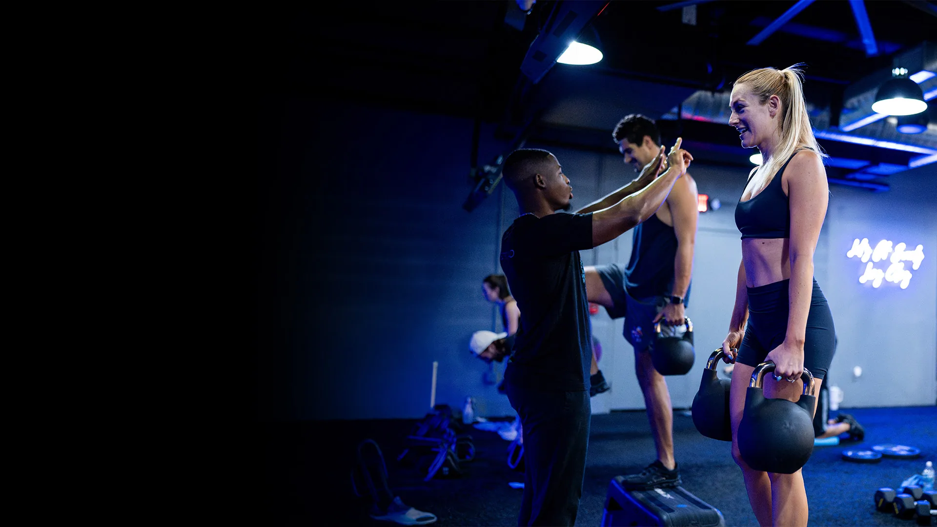 SWEAT440 coach correcting a member's kettlebell form during class